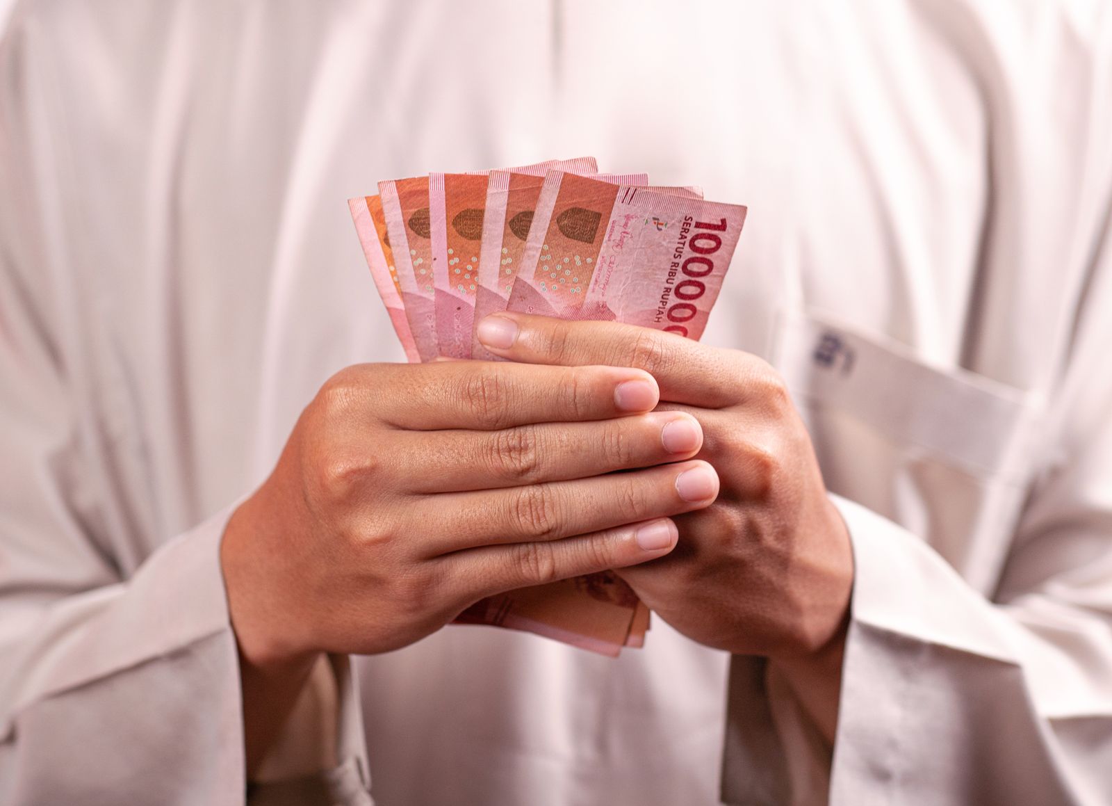 Tangan memegang lembaran uang rupiah